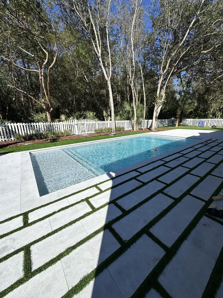 Modern rectangular inground pool with synthetic turf strips deck in Miami-Dade by Bluewater Design Studio